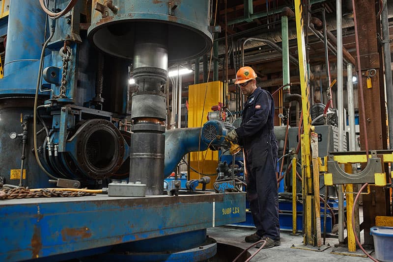 A man in a hard hat stands beside a large industrial machine.