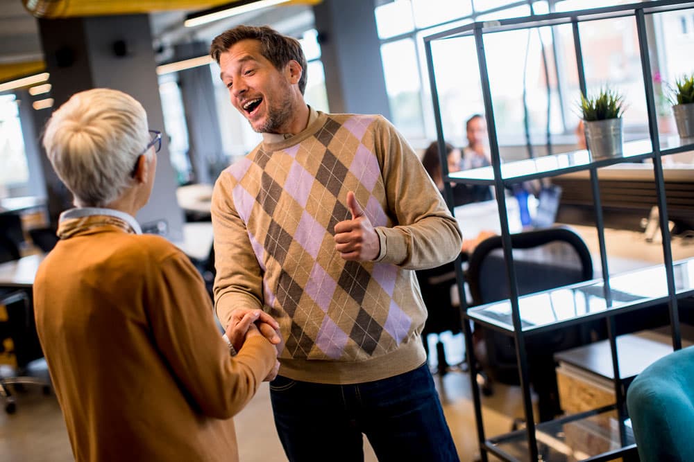 Two women smiling and conversing in an office environment, focusing on gift and hospitality regulations.
