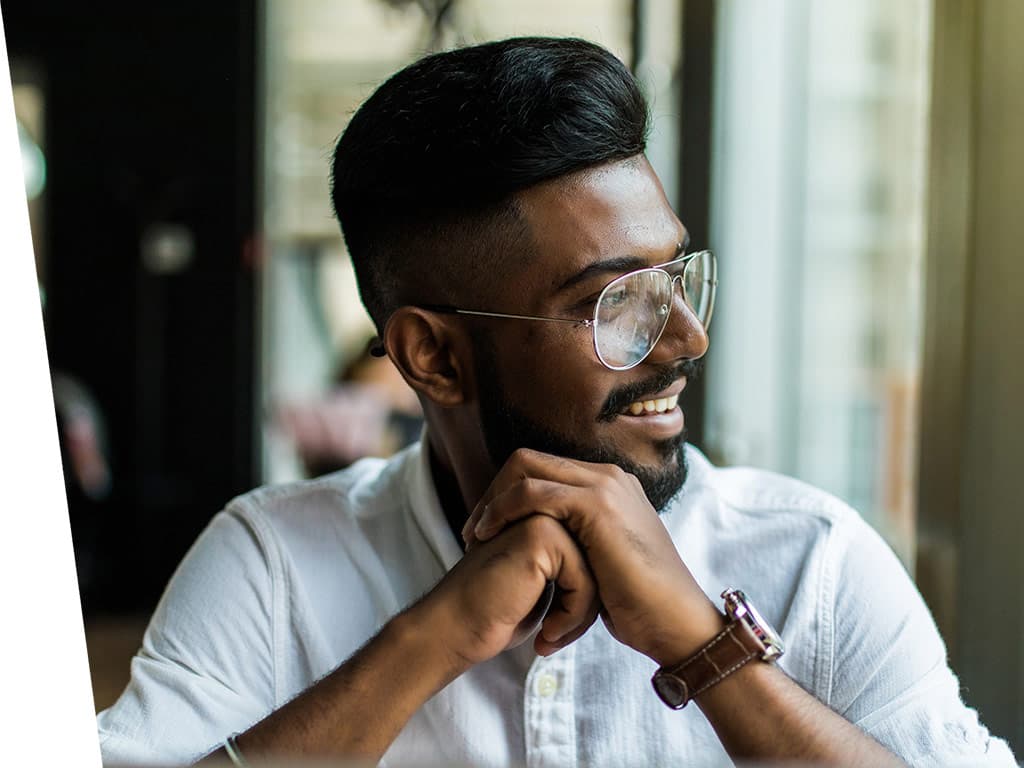 A man looking out the window of office and smiling.