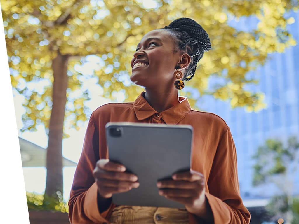 Women smiling and looking at her ipad while outside.