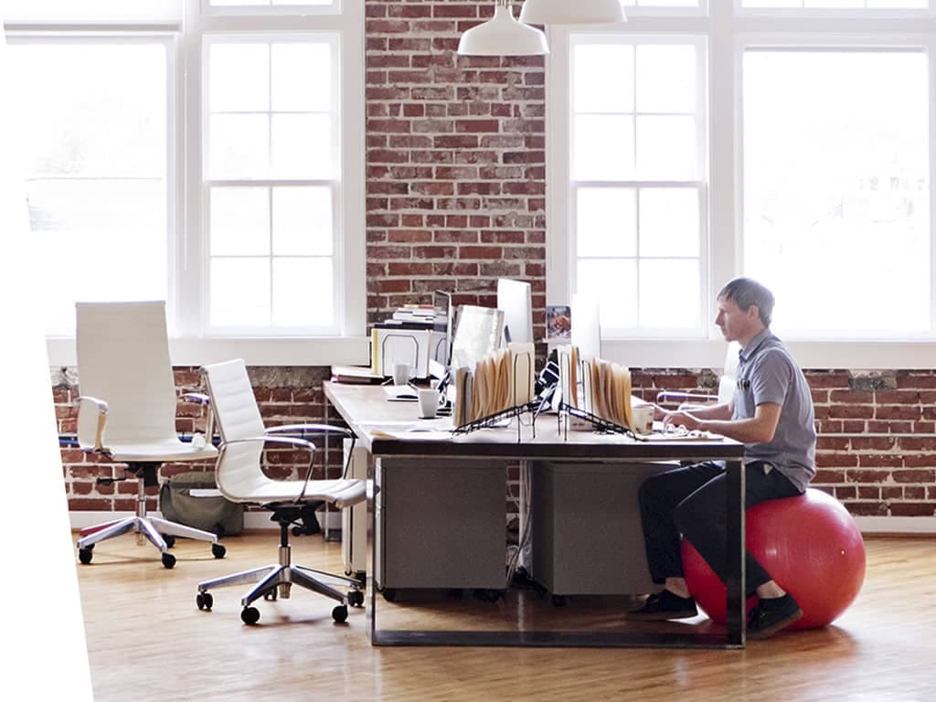 Man working at his desk in brick office building.