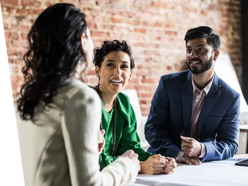 Group of 3 talking at work.