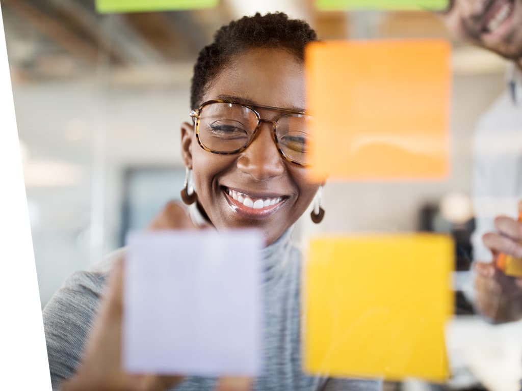 Women smiling and working with sticky notes.