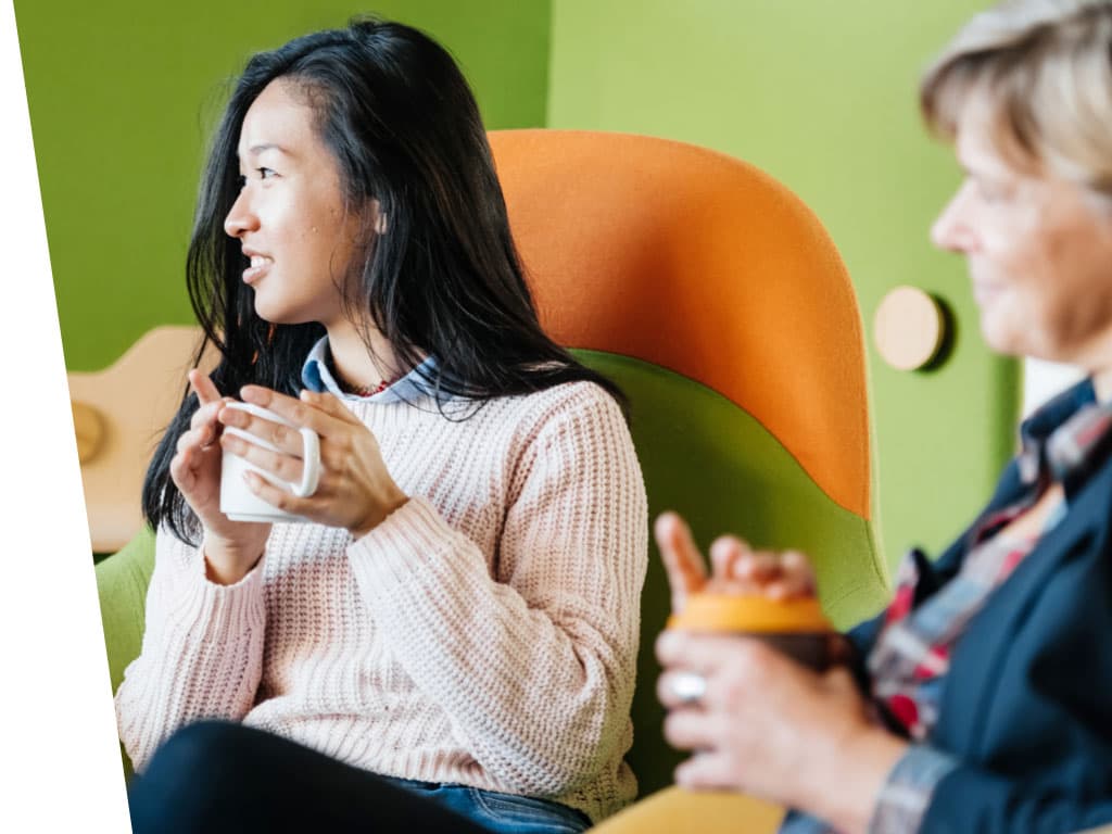 A woman and a man sitting in a chair indoors.