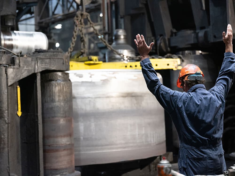 A man stands in a factory with his hands up.