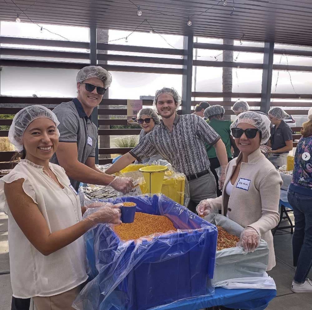 A group of people wearing plastic caps and hair nets, smiling and standing indoors.